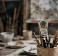 Clay sculpture, brushes in a studio, and a sculptor shaping a face.